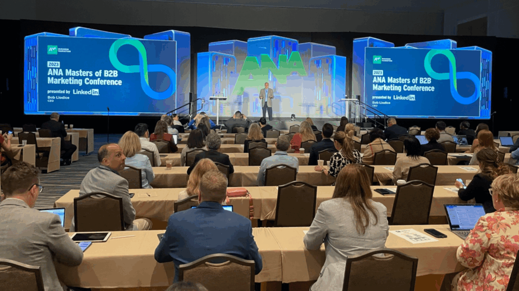 An image of the speaker presenting on stage and attendees seated at the previous ANA Masters of Marketing Conference