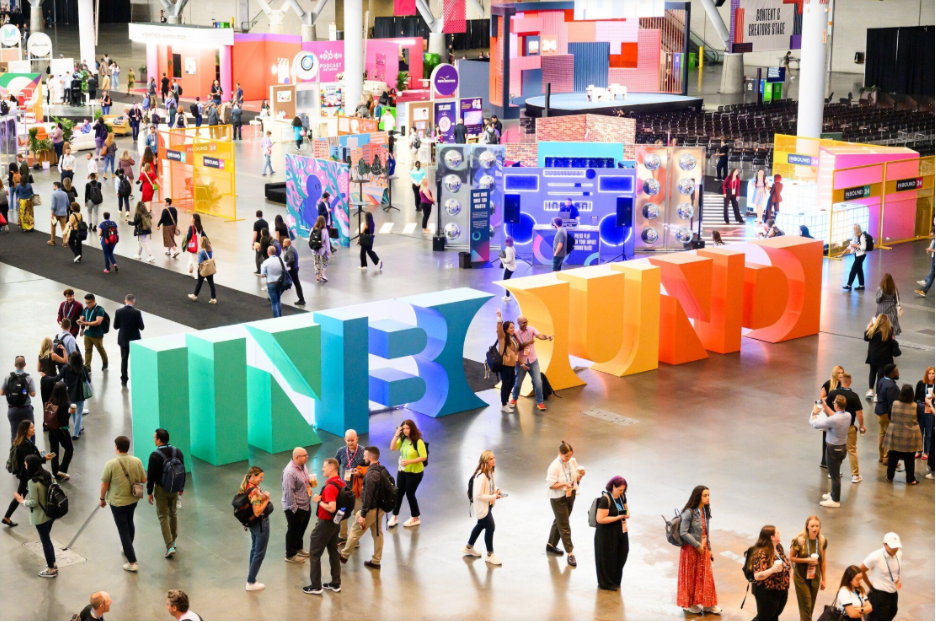 A photo of attendees walking through the colorful INBOUND conference expo floor.