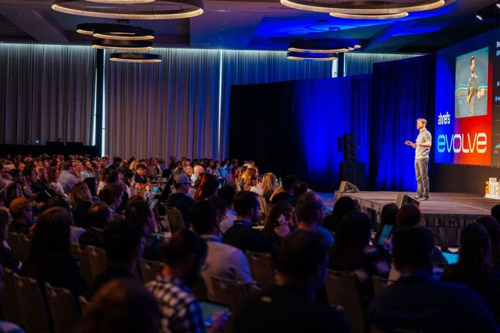 A speaker presenting on stage to an engaged audience at Ahrefs Evolve