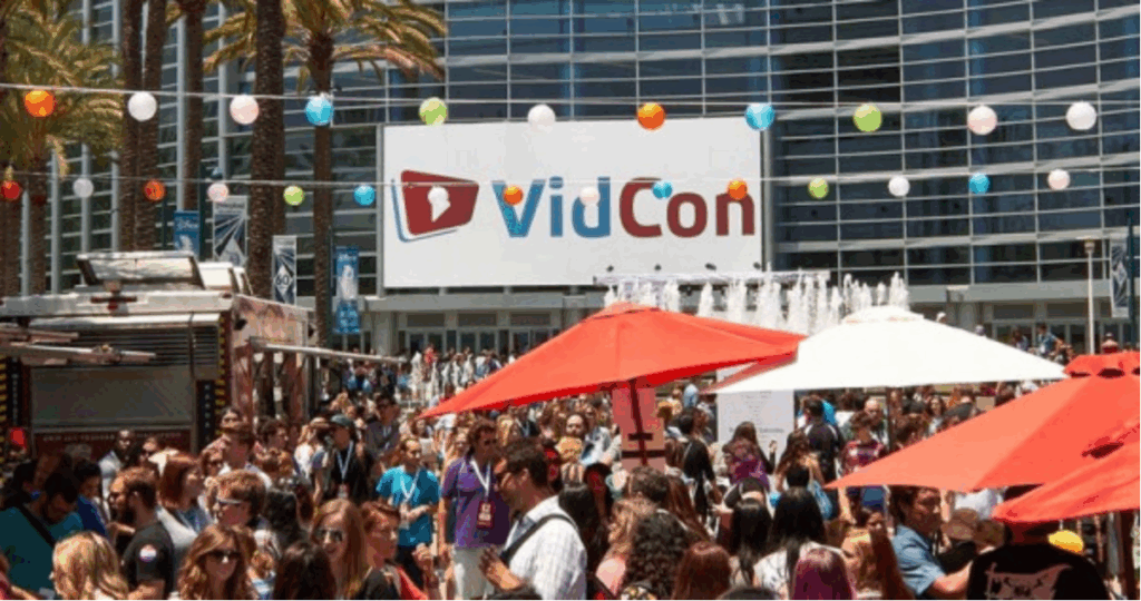 An image of the VidCon conference with crowds gathered outside under colorful lights and umbrellas.