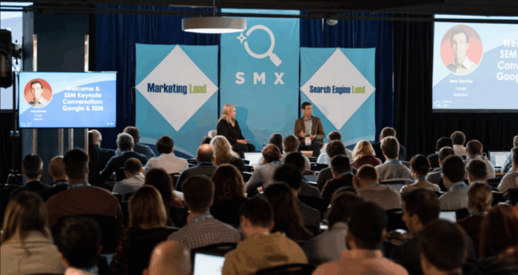 An image of the speakers on stage and attendees at the previous SMX conference