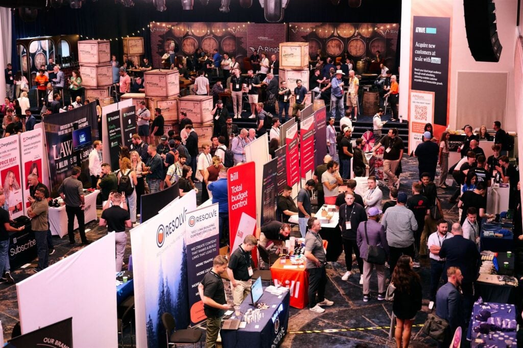 A busy expo hall filled with exhibitor booths and attendees at Affiliate Summit