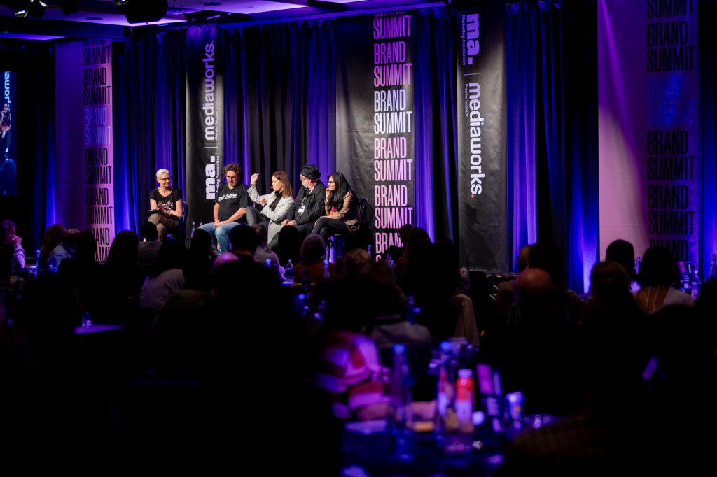 Speakers seated on stage during a panel session at The Brand Summit.