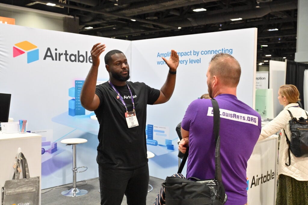 An exhibitor speaking with attendees at a booth during Content Marketing World